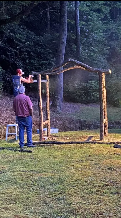 Two of the crew raising a locust arbor frame at dusk, one cutting the top rail