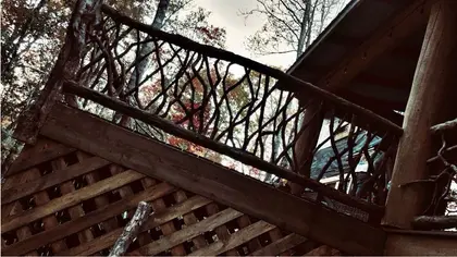 A locust branch balustrade along an elevated deck, seen from below with the covered roof above it